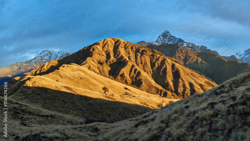 Panoramic views of Machapuchare and Mardi Himal illuminated by the dawn sun behind Korchen Hill, where the mountain shelter is located. Route to the eastern base camp of Mardi Himal.