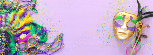 Holidays image of mardi gras masquarade, venetian mask and fan over purple background. view from above