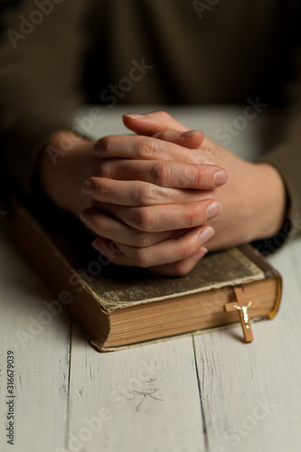 Close-up of praying hands on bible  asking for help from God.