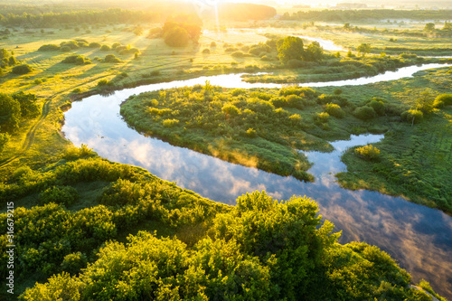 Summer morning on the river with fog, aerial view. River located between forest and green fields photo