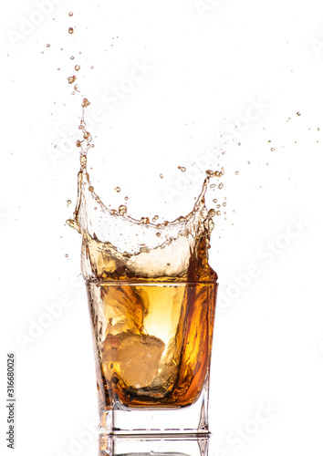 big splash from falling ice in a glass of whiskey on a white background