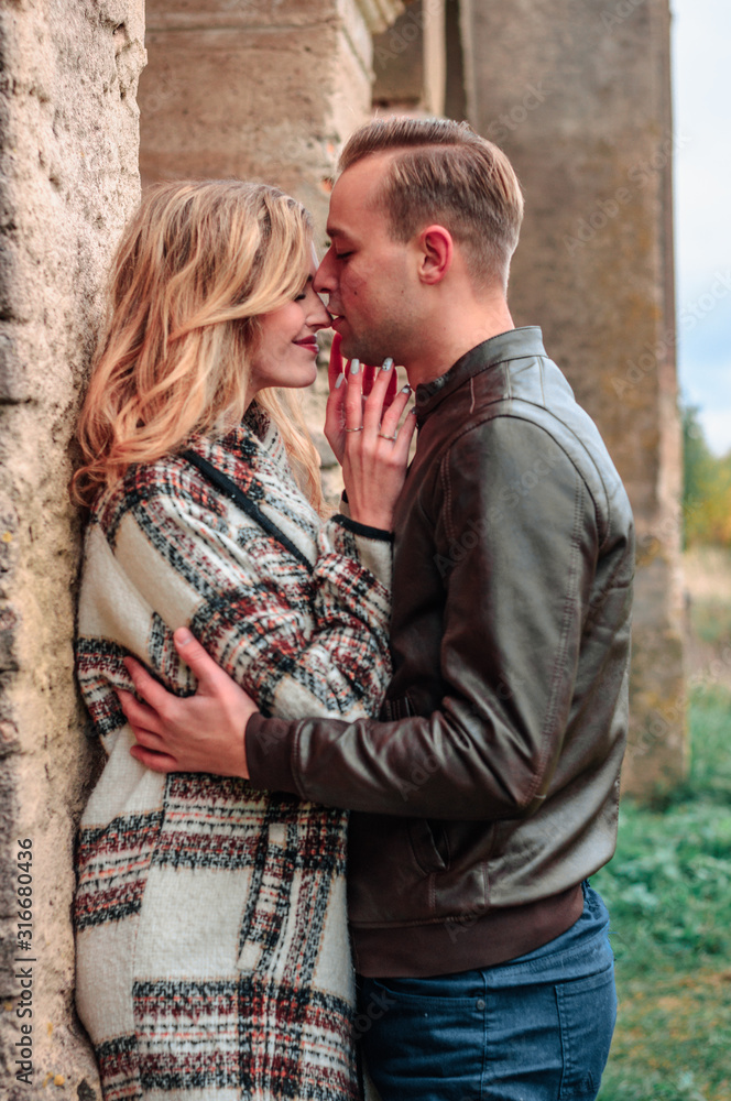 happy romantic couple in love kisses outdoors near the old building on a cold autumn day, concept of mutual love relations happy romantic couple in love kisses outdoors near the old building on a cold autumn day, concept of mutual love relations