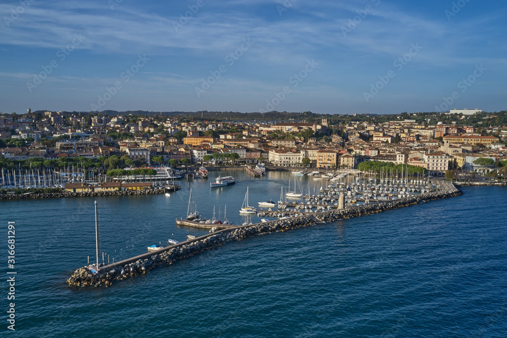 Aerial view of the city center of Desenzano del Garda, Italy. The main lighthouse of the city, boat parking in the city center. The ship leaves the city