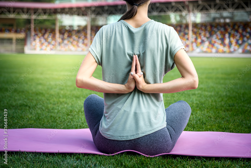 Fototapeta premium Woman on mat making morning exercises on green grass