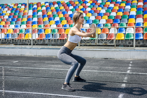 Young sportive woman making morning exercises outdoors on the stadium