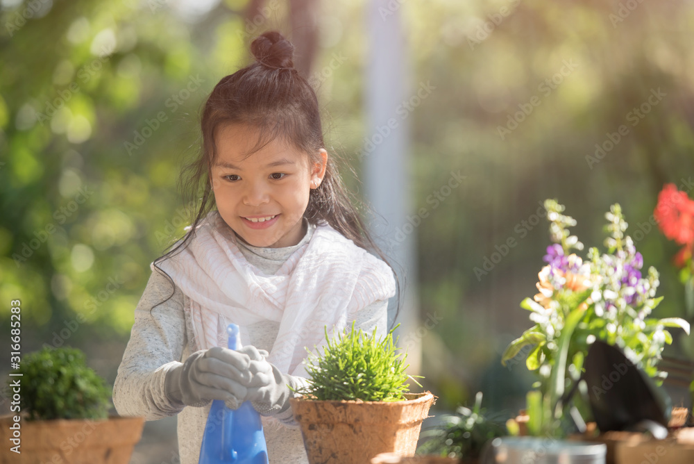 adorable 8 years old asian little girl is watering plant in pots in garden outside house, child education of nature. caring for a new life. earth day holiday concept. world environment day. ecology.
