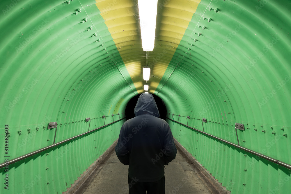Silhouette of men standing at end of tunnel Silhouette of men standing at end of tunnel