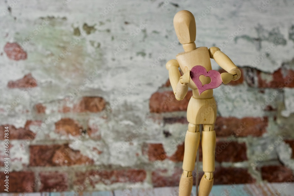 Wooden drawing figure holding pink wooden heart Wooden drawing figure holding pink wooden heart