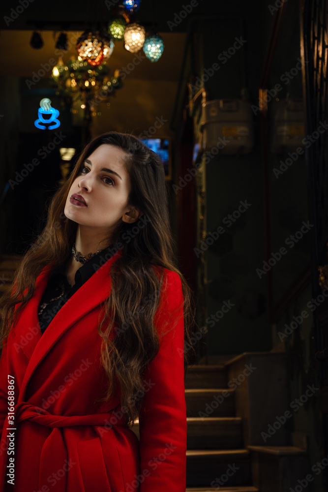 Beautiful young woman in a red coat goes outside Beautiful young woman in a red coat goes outside