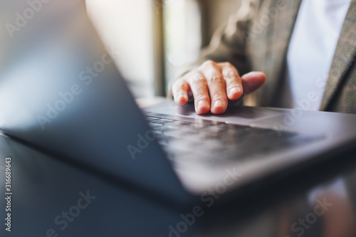 Closeup image of a woman working and touching on laptop touchpad on the table