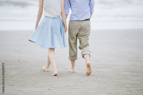 Couple stand and walk on the beach.  © Varangkana