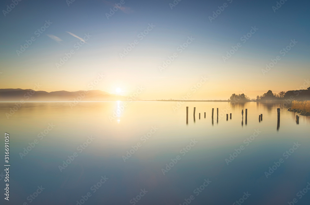 Wooden pier or jetty remains and lake at sunrise. Torre del lago Puccini Versilia Tuscany, Italy Wooden pier or jetty remains and lake at sunrise. Torre del lago Puccini Versilia Tuscany, Italy
