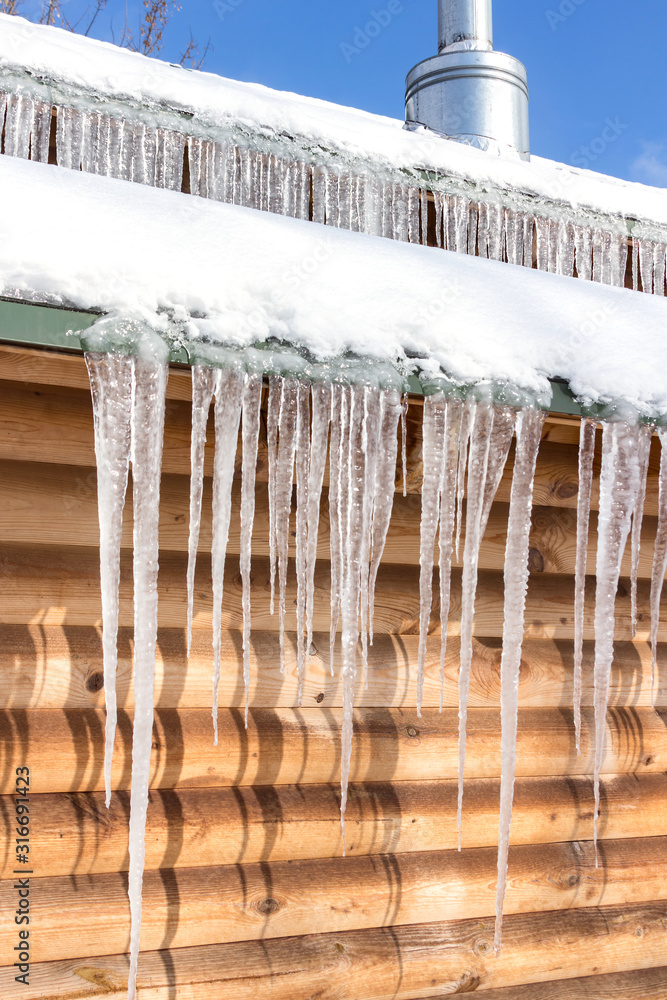 Roof with a chimney under the snow. Icing and long icicles. February Roof with a chimney under the snow. Icing and long icicles. February