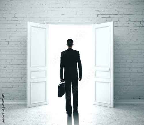 Businessman in room with open door to success. © peshkova