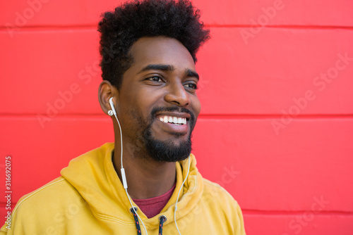 Young afro man listening to music with earphones.