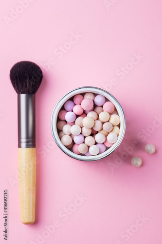 Pearl make up powder with brush on pink pastel background. Top view.