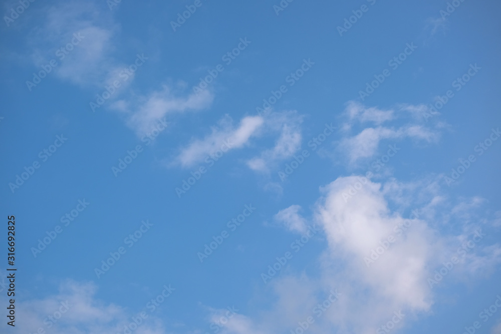 Blue sky with white clouds. Sunny background. The afternoon summer sun shines on a beautiful sky with clouds. Blue sky with white clouds. Sunny background. The afternoon summer sun shines on a beautiful sky with clouds.
