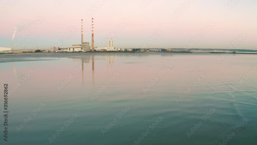 Aerial view of Poolbeg towers in Dublin. Low flying over water in Dublin Bay enables a reflection of Poolbeg. Shot in 4K. Aerial view of Poolbeg towers in Dublin. Low flying over water in Dublin Bay enables a reflection of Poolbeg. Shot in 4K.