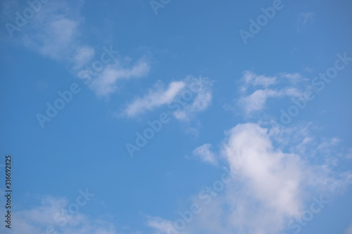 Blue sky with white clouds. Sunny background. The afternoon summer sun shines on a beautiful sky with clouds.