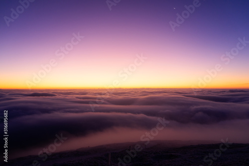 Winter landscape in Krkonose, beautiful sunrise with moon above the heavy clouds, shot from highest mountain in Czech republic called Snezka.