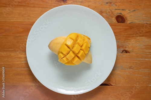 Fototapeta Naklejka Na Ścianę i Meble -  Mango yellow on dish white wood background.