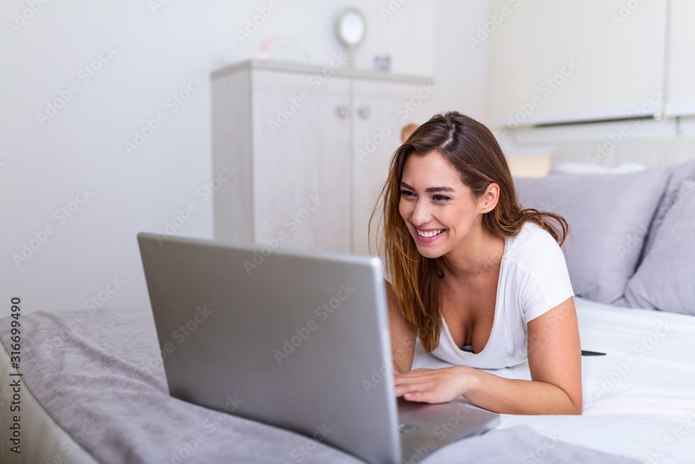 Beautiful young college student doing homework in bed at home, young pretty woman preparing school test in bedroom with laptop pc. Freelance working from home concept Beautiful young college student doing homework in bed at home, young pretty woman preparing school test in bedroom with laptop pc. Freelance working from home concept