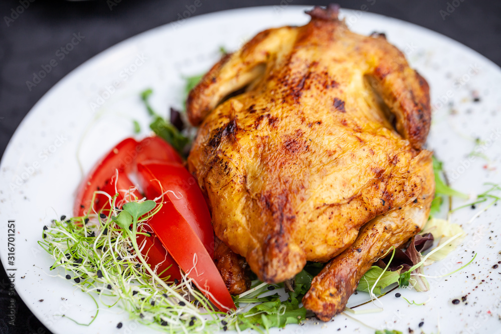 fried full chicken with vegetables and herbs in a plate on the table fried full chicken with vegetables and herbs in a plate on the table