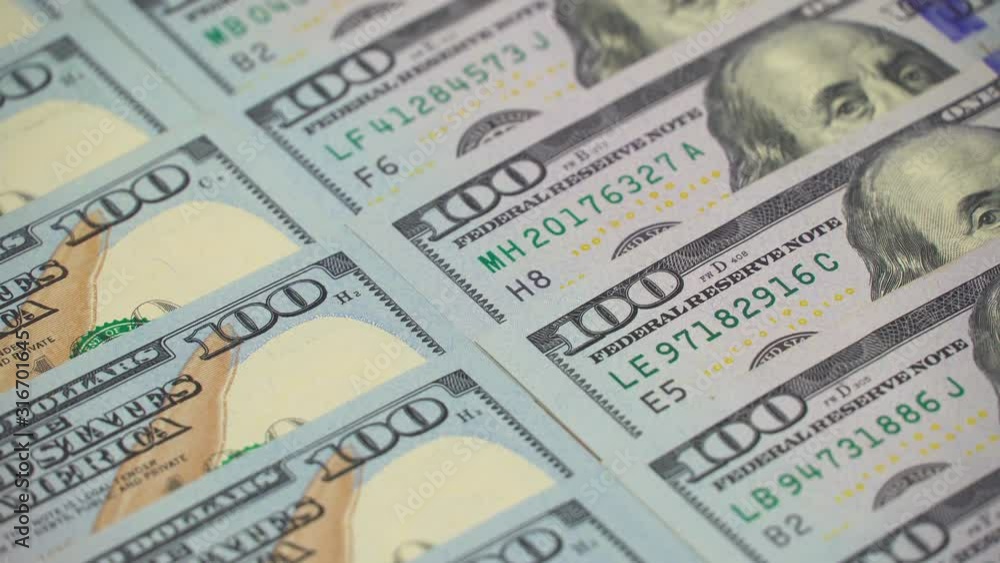 many dollars dollars dollars closeup. The camera spans from above over evenly placed bills. 100 dollars many dollars dollars dollars closeup. The camera spans from above over evenly placed bills. 100 dollars