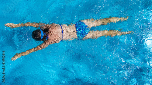 Active girl in swimming pool aerial drone view from above  young woman swims in blue water  tropical vacation  holiday on resort concept