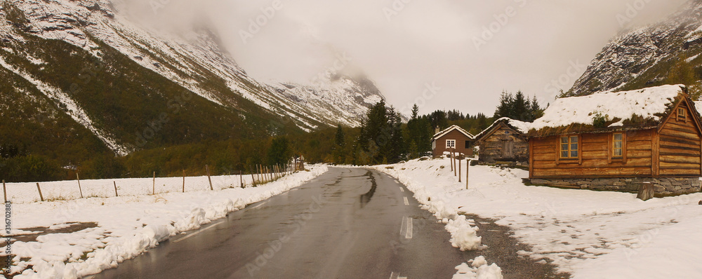 Holzhütte an Straße in winterlicher Gebirgslandschaft in Norwegen Panorama