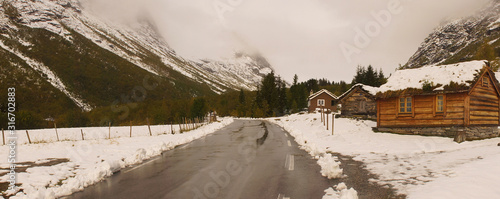 Holzhütte an Straße in winterlicher Gebirgslandschaft in Norwegen Panorama