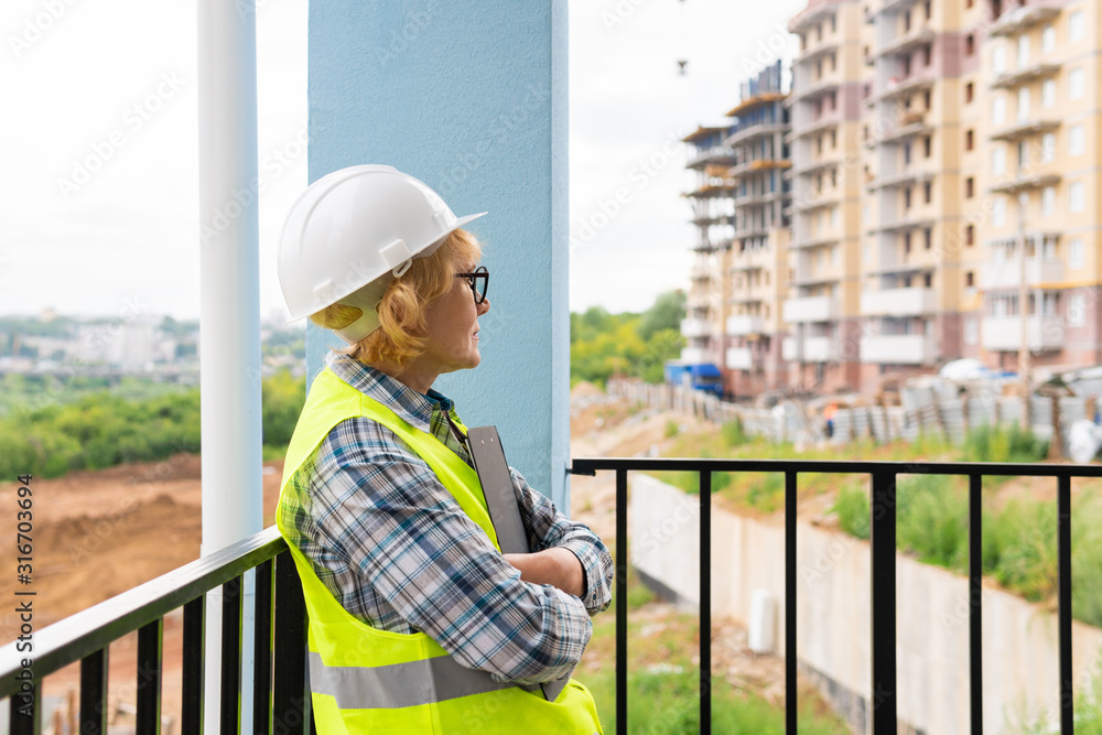A woman Builder at a construction site inspects a house made of brick A woman Builder at a construction site inspects a house made of brick