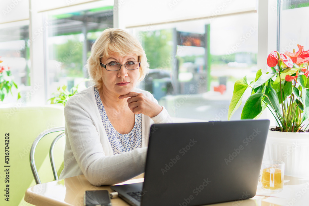 A woman with a laptop looks at a document in a cafe, office A woman with a laptop looks at a document in a cafe, office