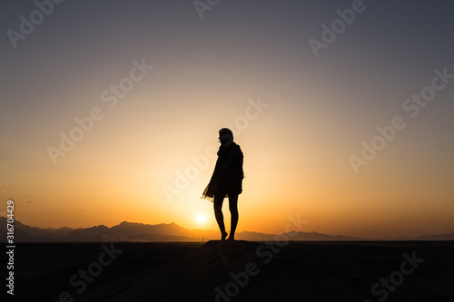 women sihouette with long scarf during sunset in desert in Yazd  Iran