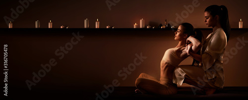 Young fit woman has Thai massage at luxury spa. Warm inviting colors, calm atmosphere, charming light. Copy space