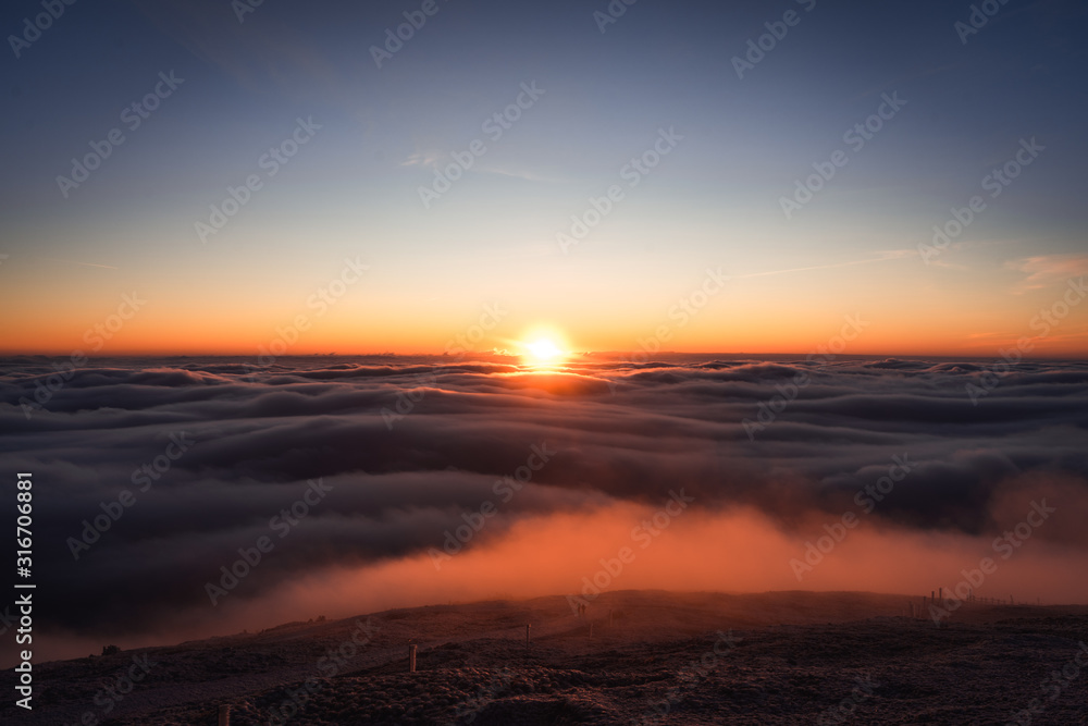 Winter landscape in Krkonose, beautiful sunrise with moon above the heavy clouds, shot from highest mountain in Czech republic called Snezka.