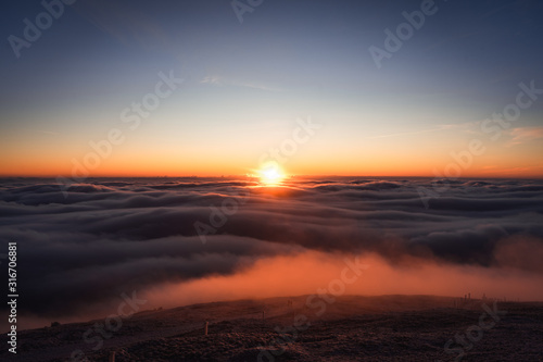 Winter landscape in Krkonose  beautiful sunrise with moon above the heavy clouds  shot from highest mountain in Czech republic called Snezka.