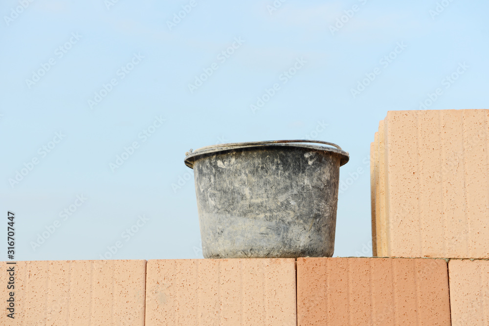 mason bucket on construction site on building stones in front of blue sky mason bucket on construction site on building stones in front of blue sky