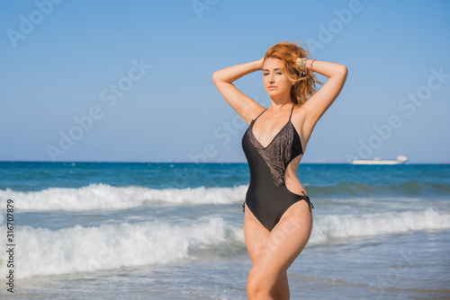 Plus size nice young woman with full hips and pretty figure in black swimsuit with fringe rest at sea, vacation and trip concept 