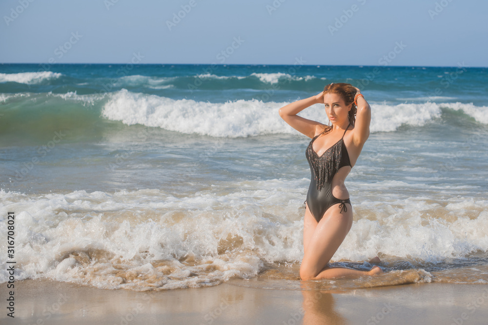 Plus size nice young woman with full hips and pretty figure in black swimsuit with fringe rest at sea, vacation and trip concept 
