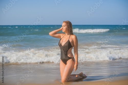 Plus size nice young woman with full hips and pretty figure in black swimsuit with fringe rest at sea, vacation and trip concept 