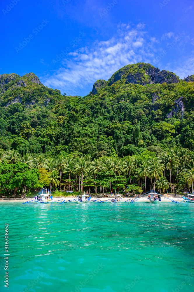 Tropical Papaya beach at paradise coast, El Nido, Palawan, Philippines. Tour A Route. Coral reef and sharp limestone cliffs.