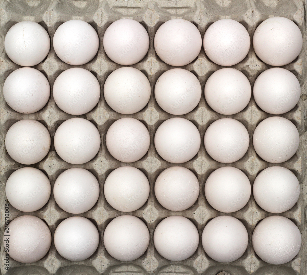 An isolated tray of eggs from recycled materials with 30 white eggs on a white background. Top view An isolated tray of eggs from recycled materials with 30 white eggs on a white background. Top view