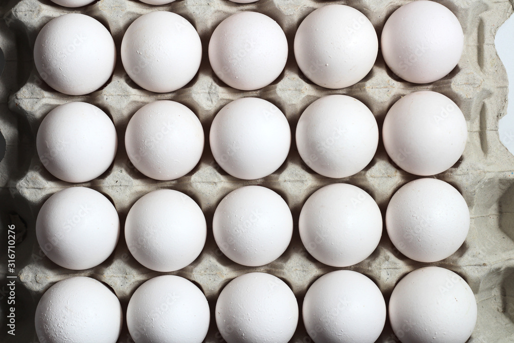 An isolated tray of eggs from recycled materials with white eggs on a white background. Top view An isolated tray of eggs from recycled materials with white eggs on a white background. Top view