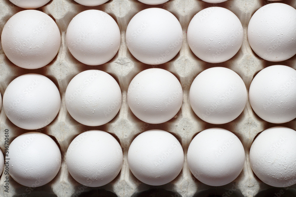 An isolated tray of eggs from recycled materials with white eggs on a white background. Top view An isolated tray of eggs from recycled materials with white eggs on a white background. Top view