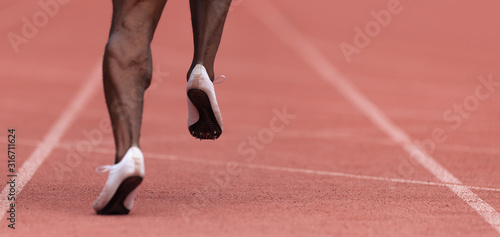 African-american male sportsman running on stadium track, dynamic run of sprinter in a stadium 