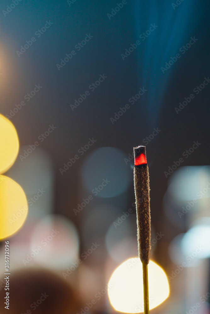 Incense stick burns against blurred candle lights. Macro photography. Incense stick burns against blurred candle lights. Macro photography.