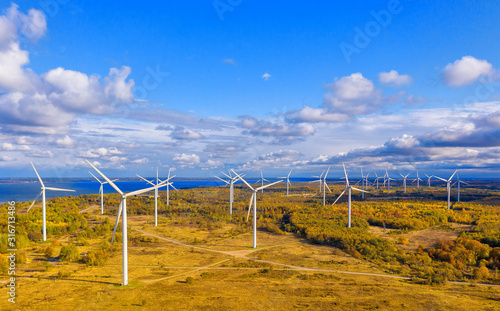 The Windmills park of Paldiski. Wind turbine farm near Baltic sea. Autumn landscape with windmills, orange forest and blue sky. Pakri peninsula, Estonia, Europe