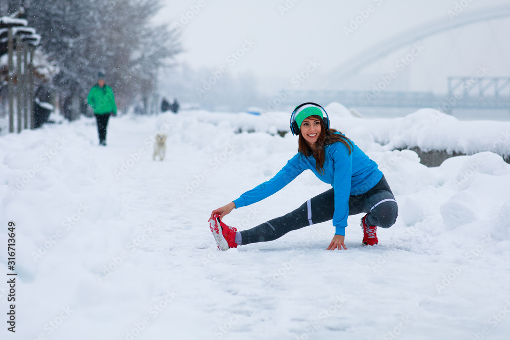 Young woman stretching arms on snowy day in the city