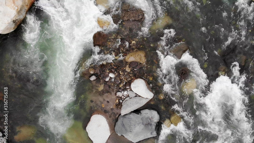 Aerial view of a river stream in the mountains. Top view of a river stream through the rocks.